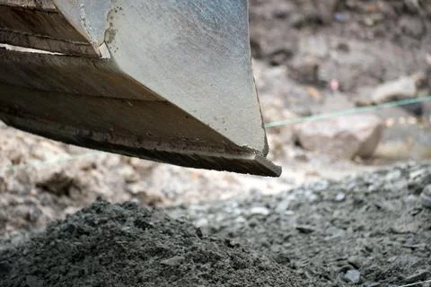 Excavator digging through soil at a construction site in daylight Stock Photos