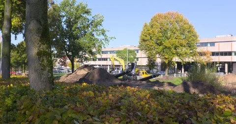 Excavator digging topsoil for rolling out a heating grid in a local community Stock Footage 120063037