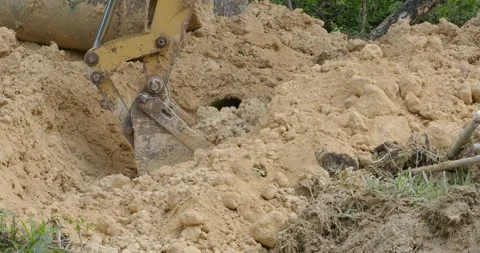 Excavator digging wet ground for pipe rainwater drainage in countryside. Stock Footage 302304692