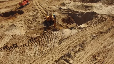Excavator digging works quarry Orange sand soil rock heavy industry Aerial drone Stock Footage