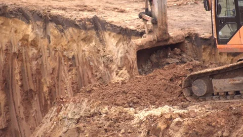 An excavator digs clay soil in a foundation pit to build a foundation. Excavator Stock-Footage 129489320