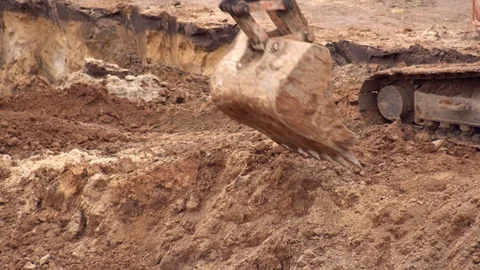 An excavator digs clay soil in a foundation pit to build a foundation. Excavator Stock Footage 129687419