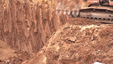 An excavator digs clay soil in a foundation pit to build a foundation. Excavator Stock Footage 129687985