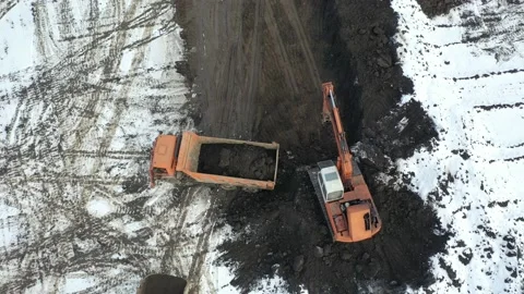 The excavator digs a pit and loads the soil into a dump truck. Drone video. Stock Footage 147094116
