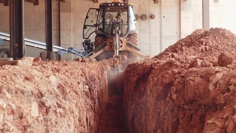 An Excavator Digs Red Dirt Out Of A Trench At A Construction Site Stock Footage 87482003