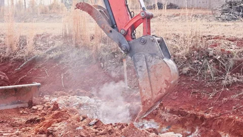 Excavator digs into red soil at construction site during digging trench 스톡 동영상 339010279