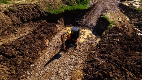 Excavator drags stones using its front ripper while the aerial camera slowly Stock Footage 307386031