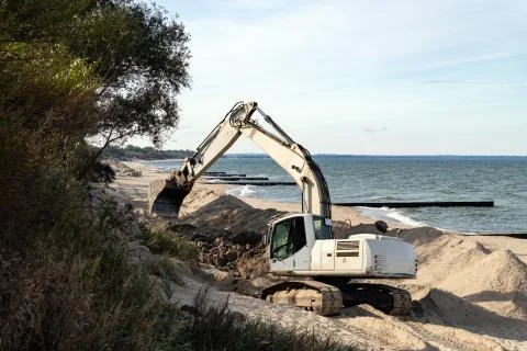 Excavator dripping on the seashore. Construction work on the coast using heav Stock Photos