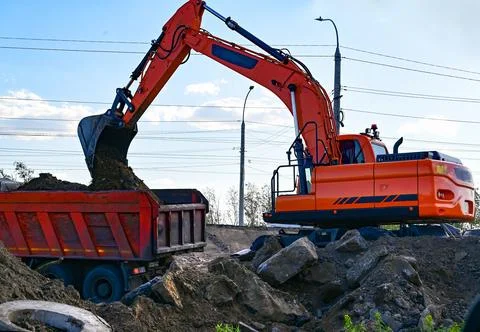 Excavator during earthmoving at open pit on blue sky background. Constructi.. Stock Photos