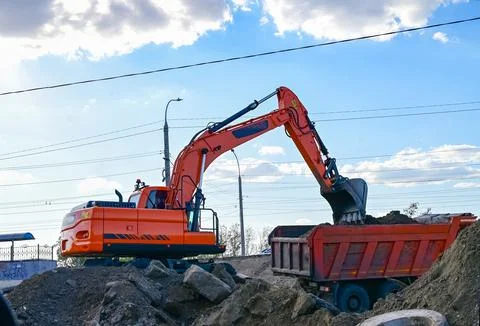 Excavator during earthmoving at open pit on blue sky background. Constructi.. Stock Photos