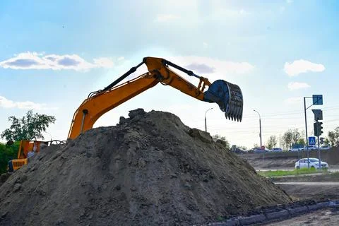 Excavator during earthmoving at open pit on blue sky background. Constructi.. Stock Photos