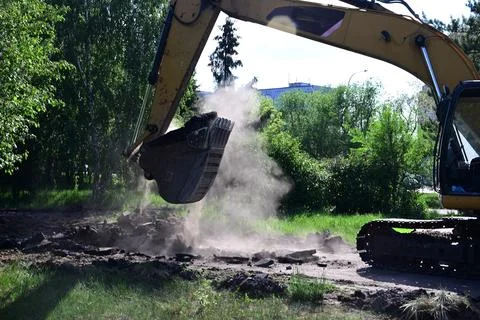 Excavator during earthmoving at open pit on blue sky background. Constructi.. Stock Photos