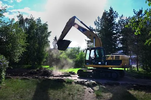 Excavator during earthmoving at open pit on blue sky background. Constructi.. Stock Photos