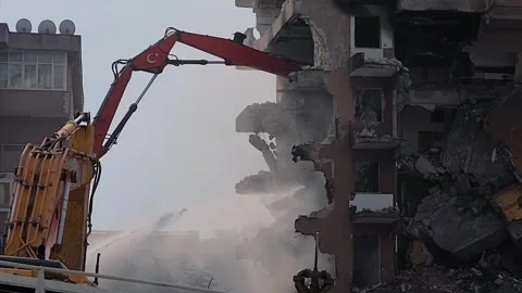 Excavator with hydraulic crusher tears down residential building: slow motion Stock Footage 344345669
