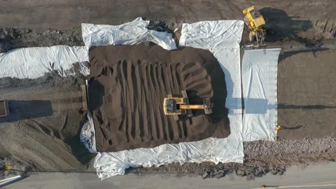 Excavator leveling soil while dump truck unloading gravel on road construction. Stock Footage 158973456