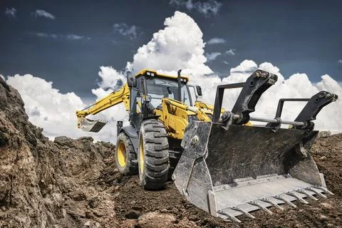 An excavator loader is working at a construction site. It is clearing dirt .. Stock Photos