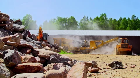 Excavator loading aggregate material in a rock crusher to pulverize into Stock Footage 221817091