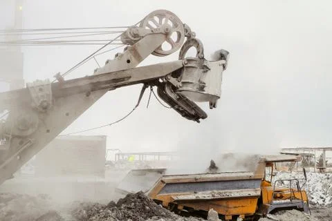 Excavator loading into a big mining dump truck. Work in heavy industry. Stock Photos