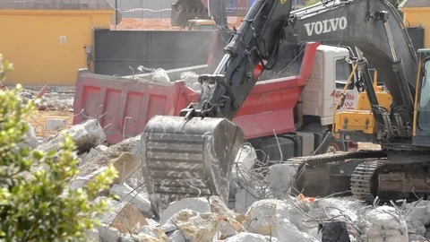 Excavator loading debris into a construction truck during a demolition Stock Footage