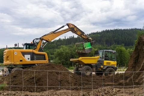 Excavator loading dirt into a yellow dump truck at a construction site Stock Photos