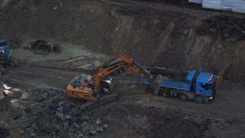 Excavator loading dump truck on construction site at evening. Aerial drone Stock Footage 334527401