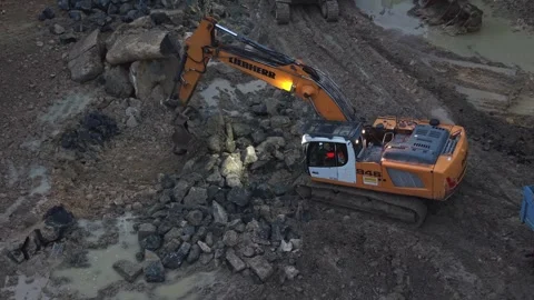Excavator loading dump truck on muddy construction site at dusk Stock Footage 334548587