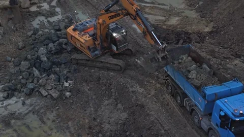 Excavator loading dump truck with rocks at dusk Stock Footage 334549830