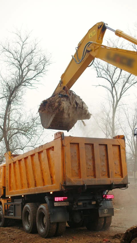 Excavator Loading Dump Truck with Soil Stock Footage 296755399
