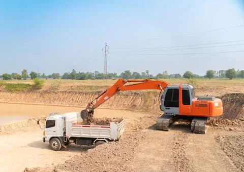 Excavator loading dumper trucks. Stock Photos