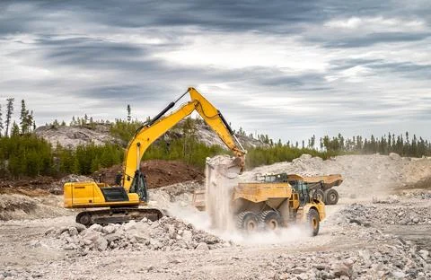 Excavator loading dumpers with blasted stone Stock Photos