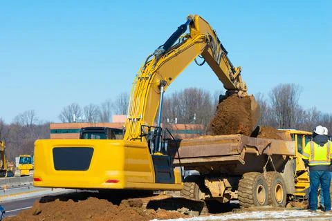 Excavator loading earth into big dump truck Stock Photos