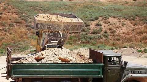 Excavator loading heavy duty dumper truck with rocks Stock Footage