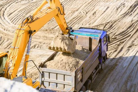 Excavator loading sand bucket in the back of the truck Stockfoto's