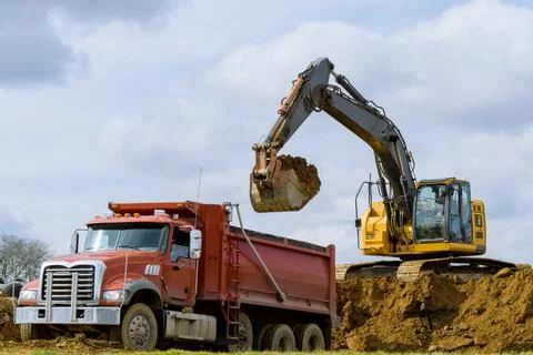Excavator loading sand in rear-end tipper Stock Photos