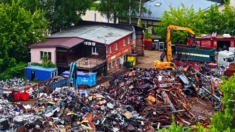 Excavator loading scrap metal from junkyard pile into a container truck Stock Footage 339646789