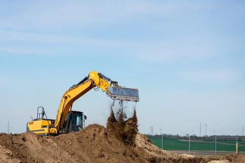 Excavator loading soil on construction site under clear sky Fotos Stock