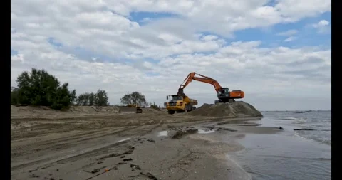 Excavator Loading Volvo Truck on Cloudy Beach Stock Footage 297415817