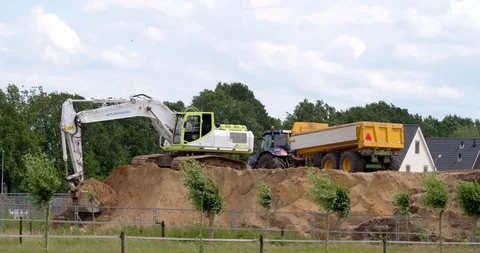 Excavator loading yellow earth into tractor and trailer at construction site Stock Footage 109838085