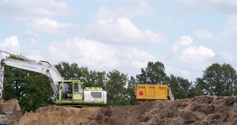 Excavator loading yellow earth into trailer at construction site Vídeo Stock 109844518