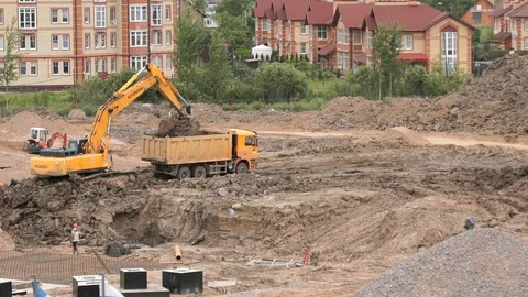 Excavator loads clay using bucket into dump truck Stock Footage