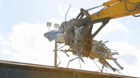 Excavator machine dropping metal scrap into truck from building demolition A Stock Footage 114925469