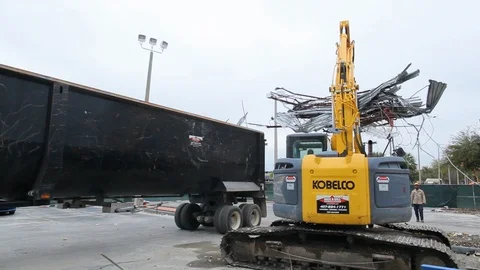 Excavator machine dropping metal scrap into truck from building demolition B Stock Footage 114925582