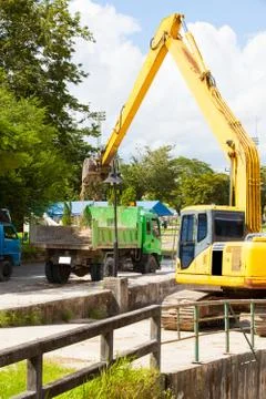 Excavator machine loading soil or sand into truck body Stock Photos