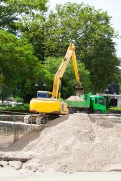 Excavator machine loading soil or sand into truck body Stock Photos
