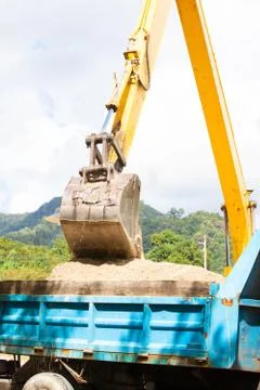 Excavator machine loading soil or sand into truck body Stock Photos