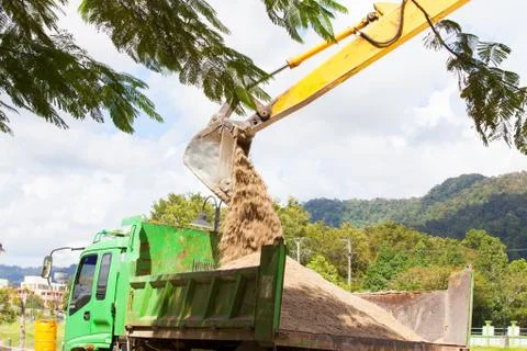 Excavator machine loading soil or sand into truck body Stock Photos