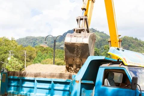 Excavator machine loading soil or sand into truck body Stock Photos