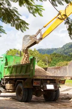 Excavator machine loading soil or sand into truck body Stock Photos