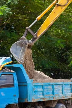Excavator machine loading soil or sand into truck body Stock Photos