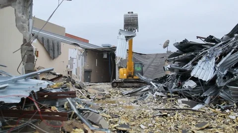 Excavator machine moving rubble scrap to a pile from building demolition B Stock Footage 114926174